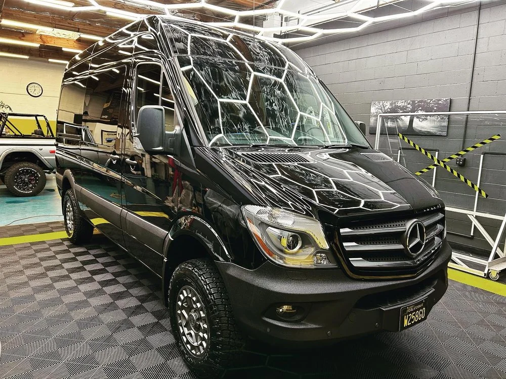 Black Mercedes-Benz Sprinter van with off-road wheels in the Artec Automotive service bay