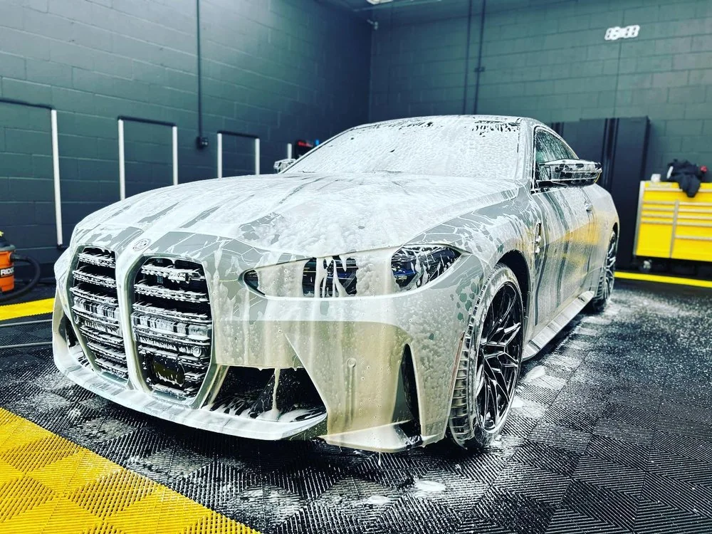 BMW M car covered in snow foam during the wash stage before paint correction