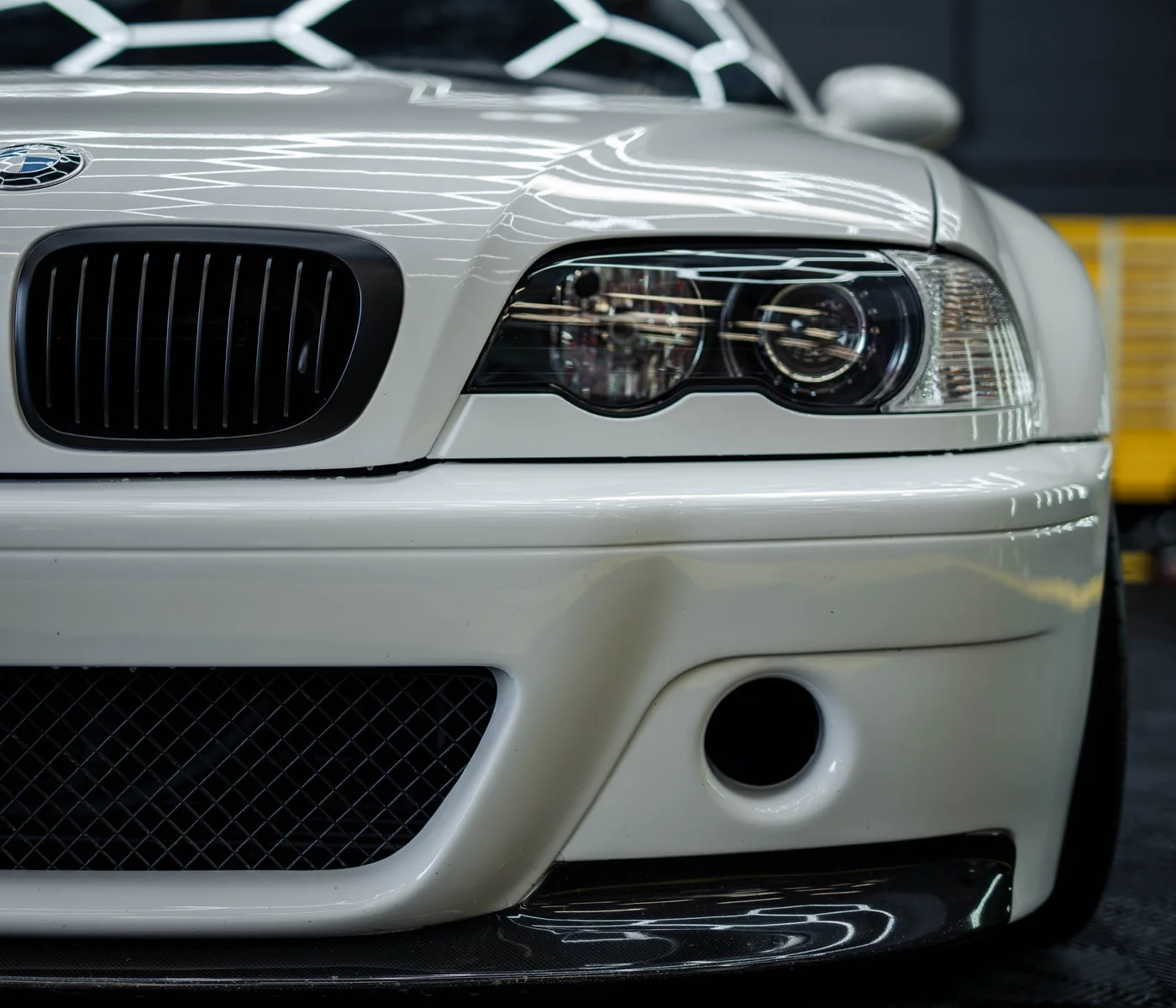 Front bumper and headlight detail of a white BMW E46 M3