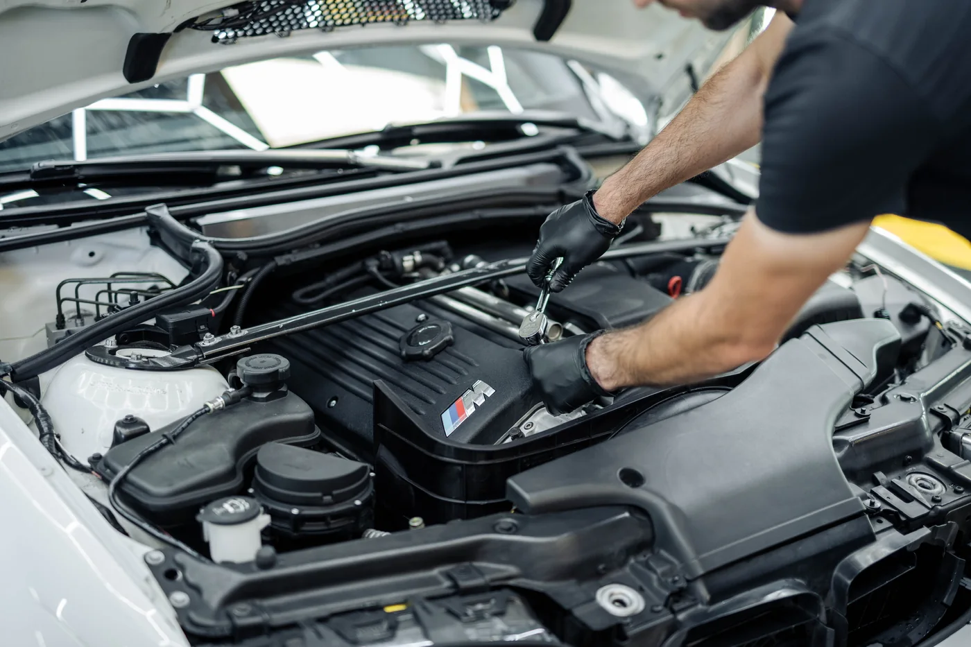 Technician working in the engine bay of a car during scheduled service