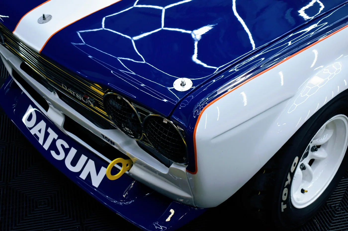 Rear of a blue and white Datsun race car on the shop floor