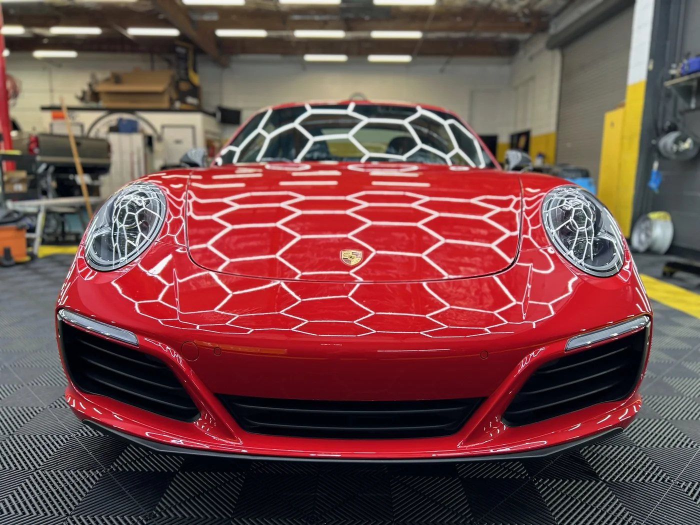 Red Porsche 911 with paint protection film laid over the front end during installation