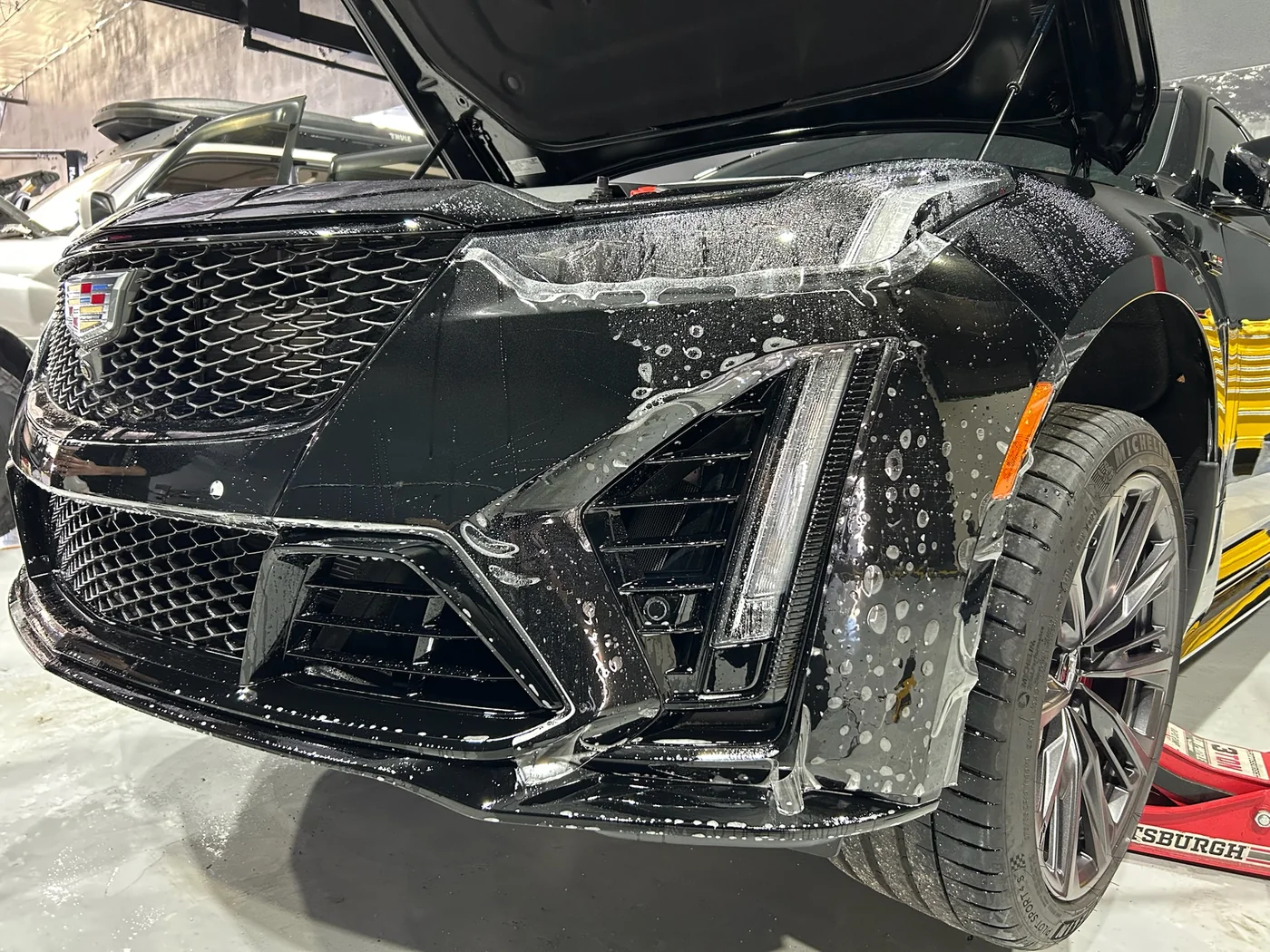 Paint protection film being wet-applied to a carbon front splitter at Artec Automotive