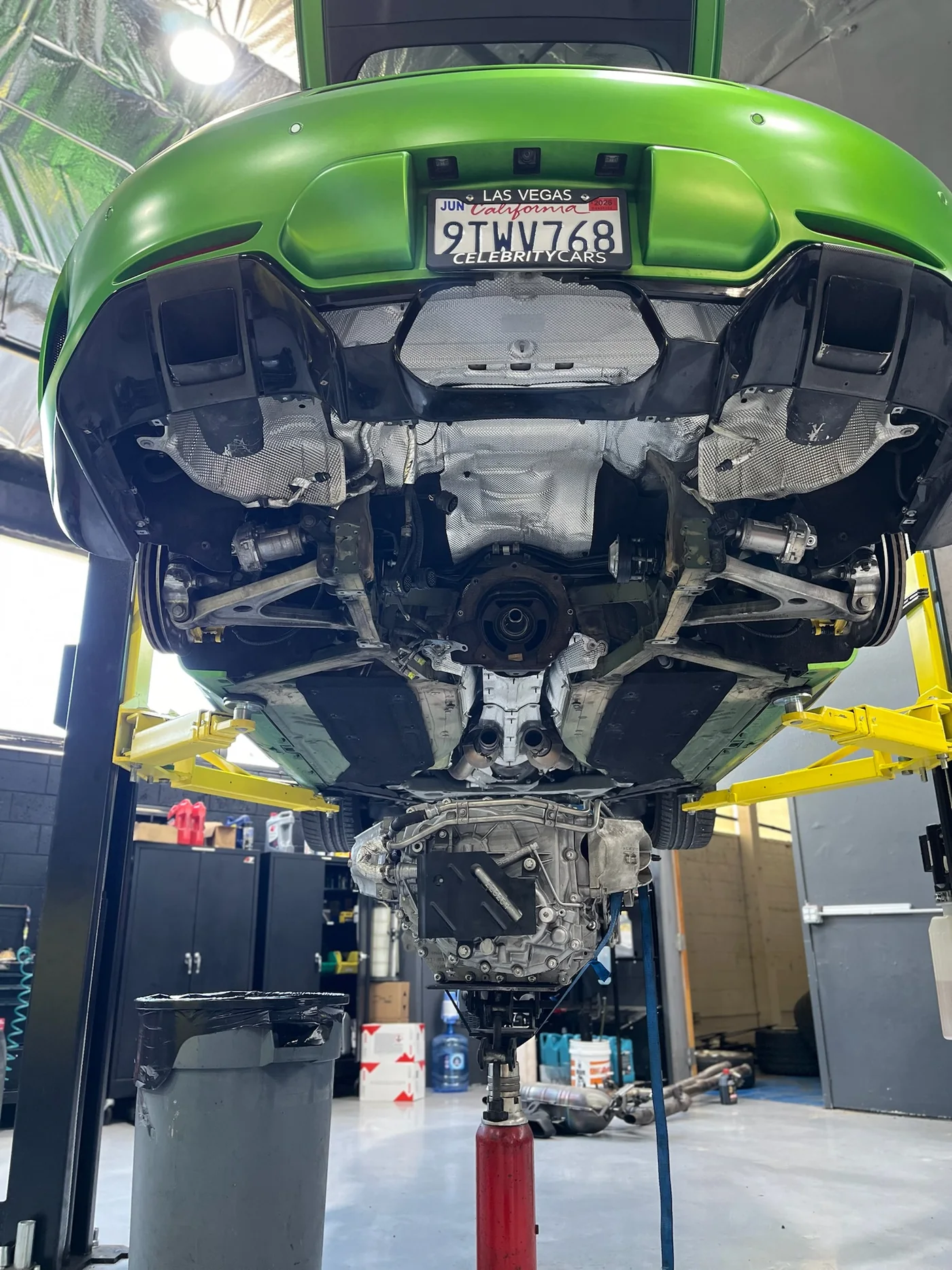 Underside of a green Mercedes-AMG GT raised on a lift during service at Artec Automotive