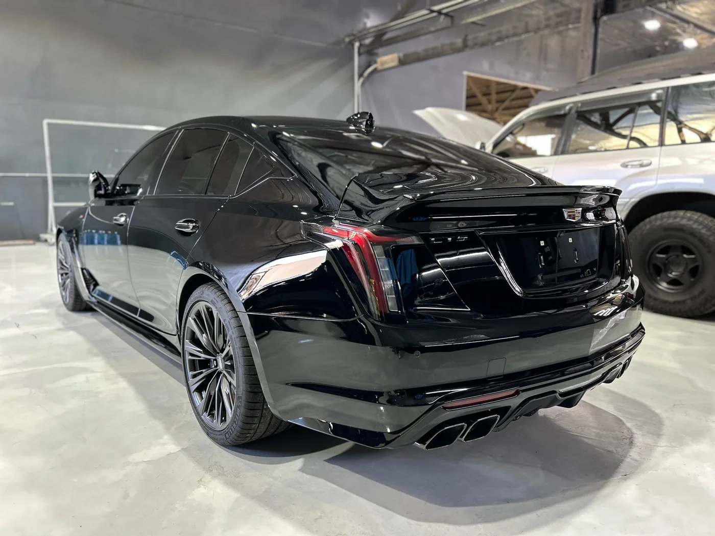 Rear of a black Cadillac CT5-V Blackwing reflecting the workshop after ceramic coating