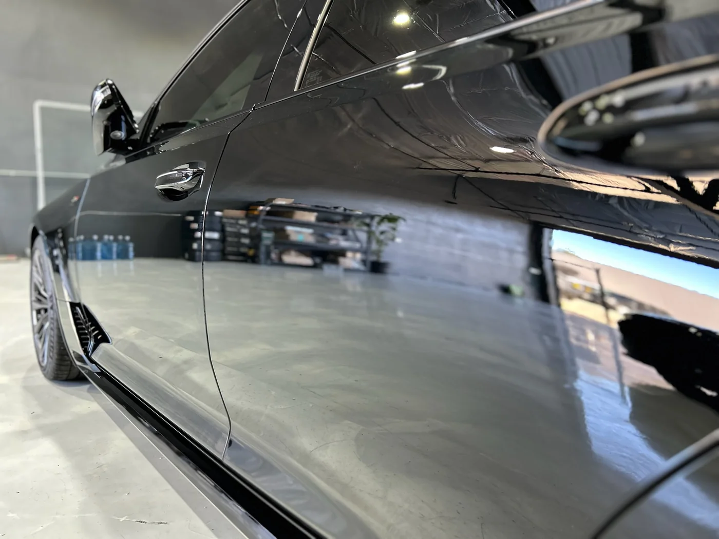 Black paintwork reflecting overhead lighting after multi-stage paint correction
