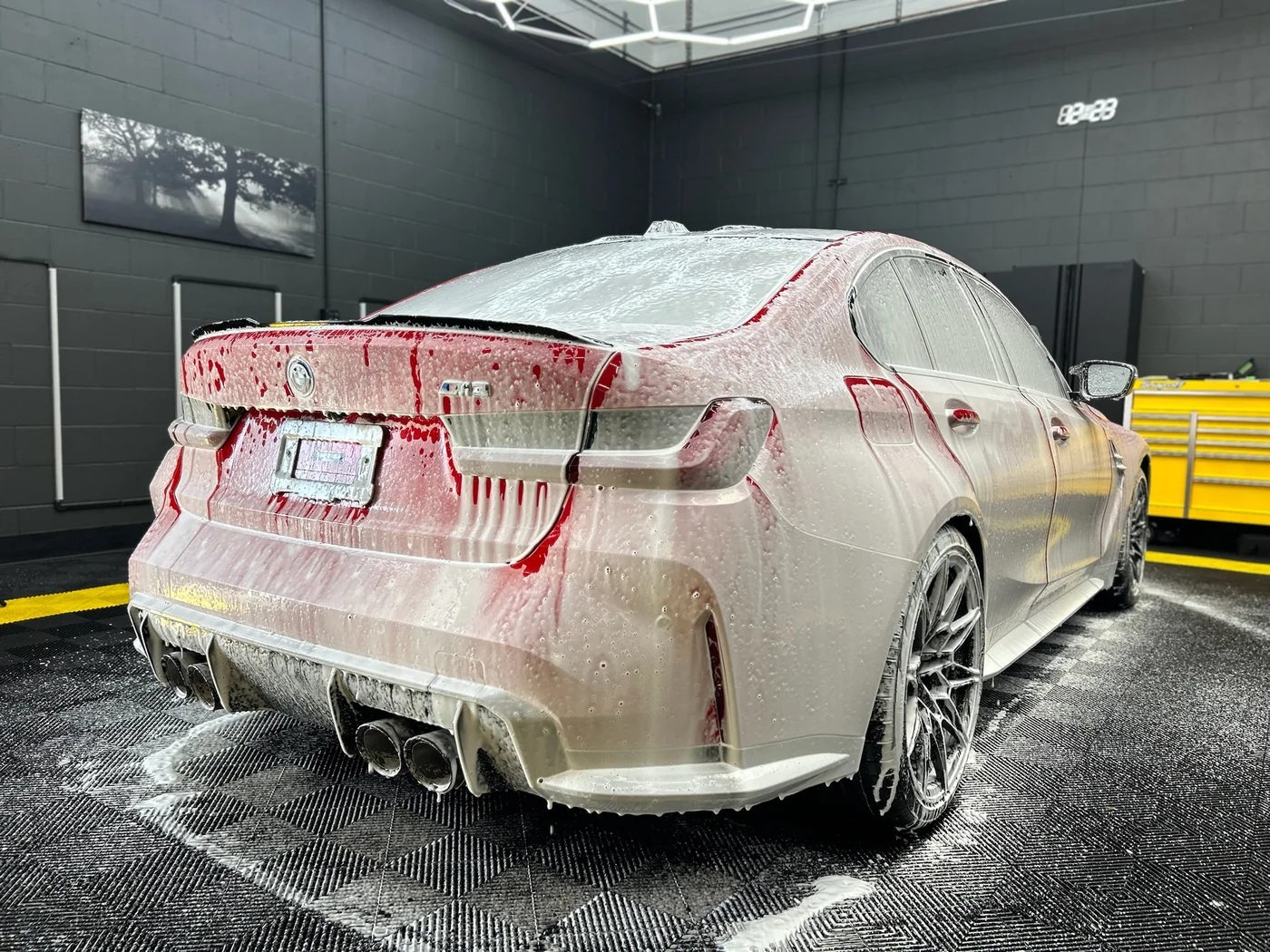 Red BMW M5 covered in snow foam during the decontamination wash stage