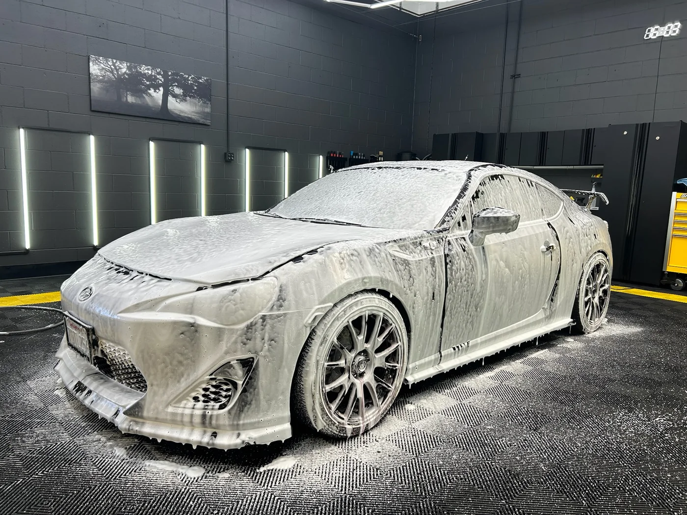 Grey sports car covered in snow foam before paint correction at Artec Automotive
