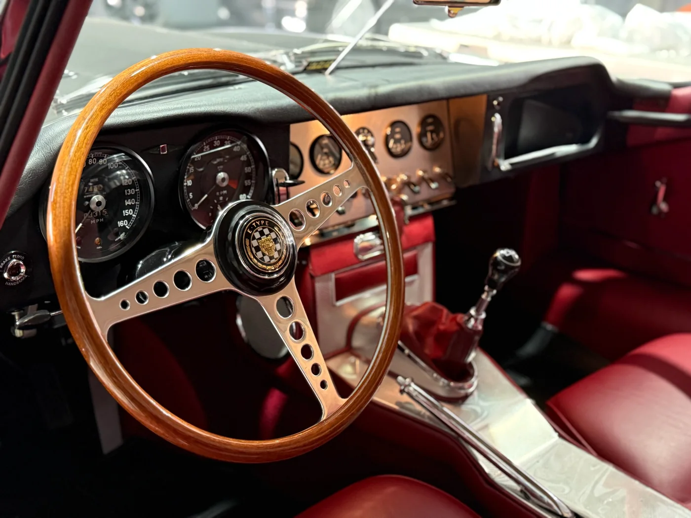 Wood-rimmed steering wheel and red leather interior of a restored Jaguar E-Type