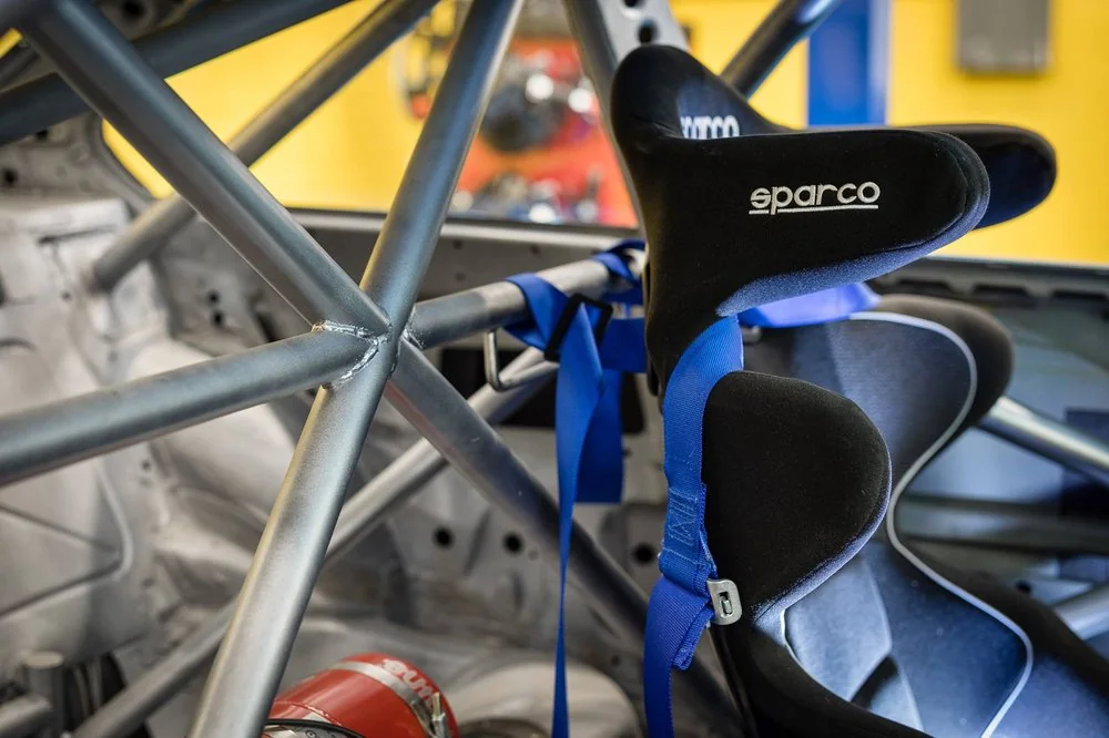 Sparco racing seat and blue harness fitted inside a welded roll cage
