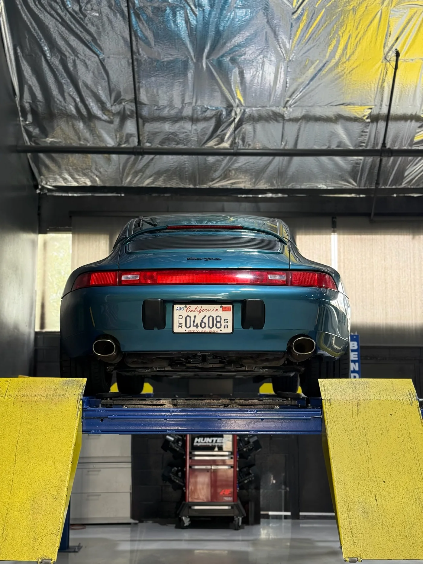 Green Porsche 911 raised on a lift for service at Artec Automotive in Belmont, CA