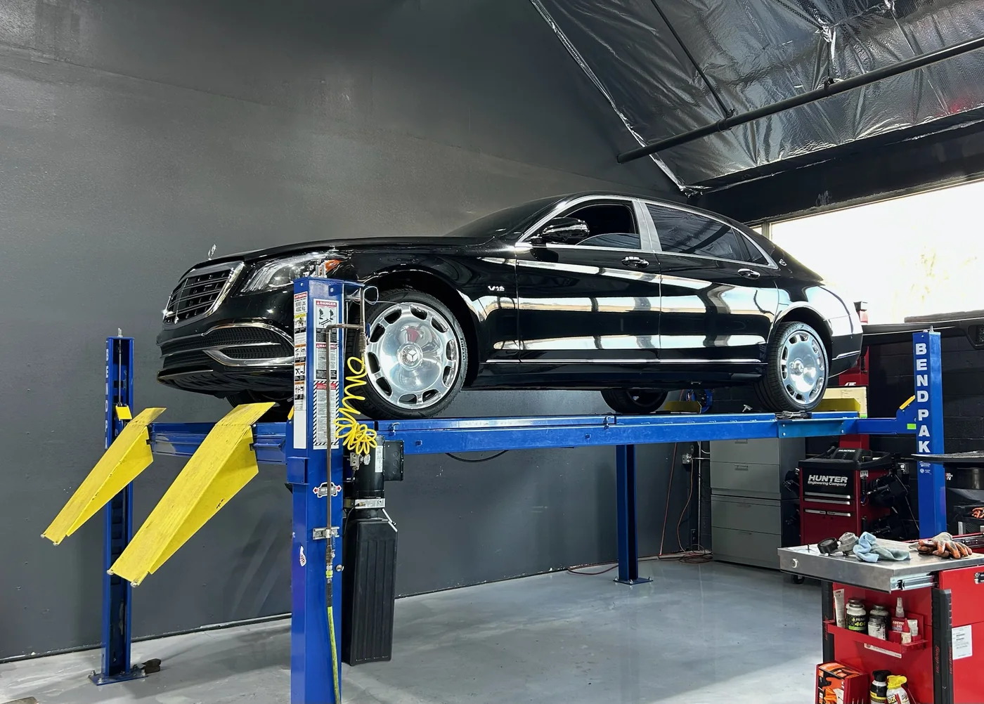 Black Mercedes-Maybach raised on a two-post lift for service at Artec Automotive