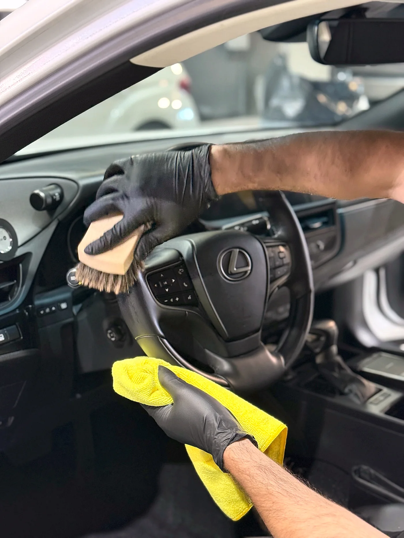 Technician in gloves cleaning the steering wheel and interior of a Lexus at Artec Automotive