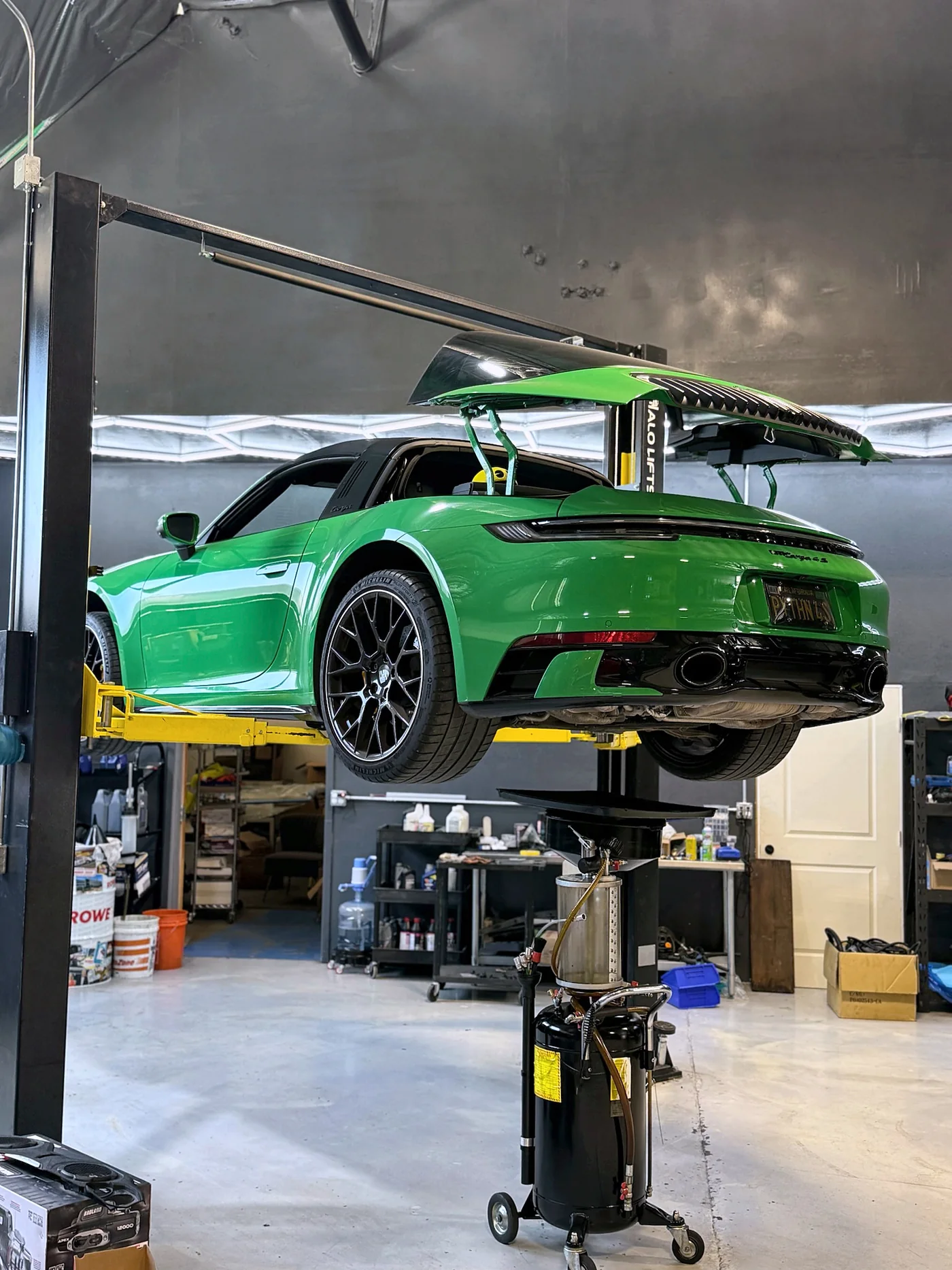 Green Porsche 911 GT3 RS raised on a two-post lift in the Artec Automotive workshop
