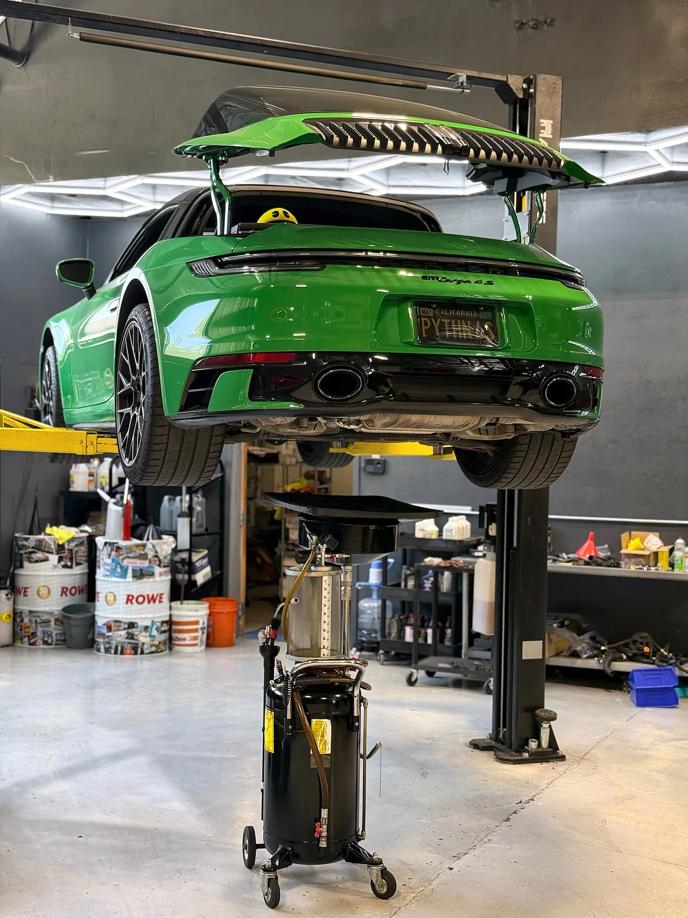 Underside of a green Porsche 911 GT3 RS showing the exhaust and rear diffuser on a lift