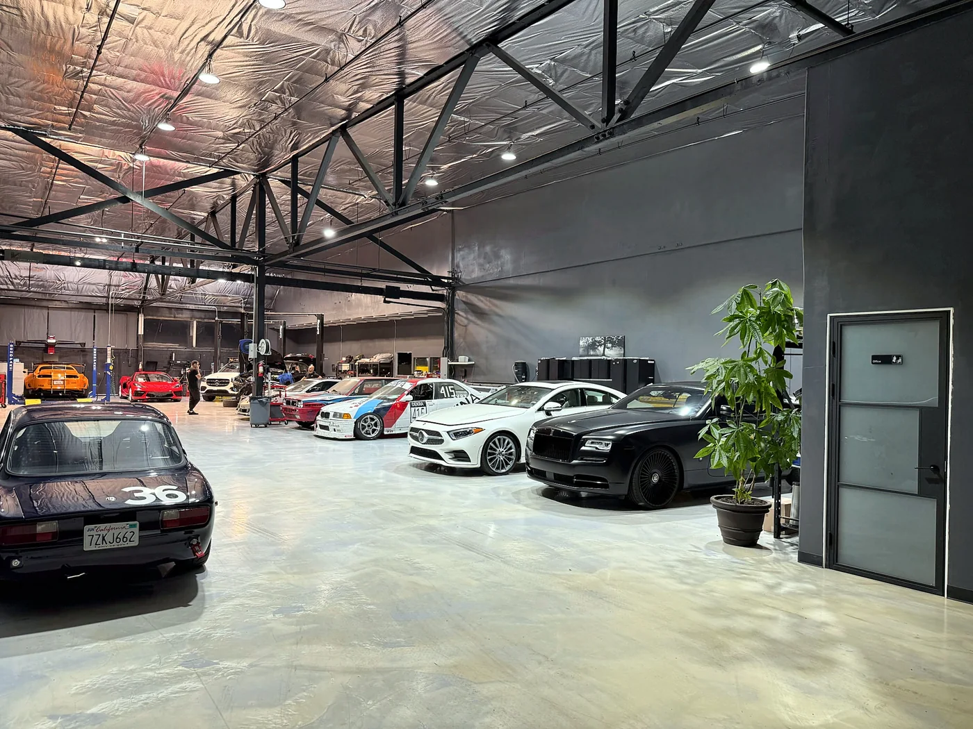 Row of exotic and performance cars parked inside the Artec Automotive shop in Belmont, CA