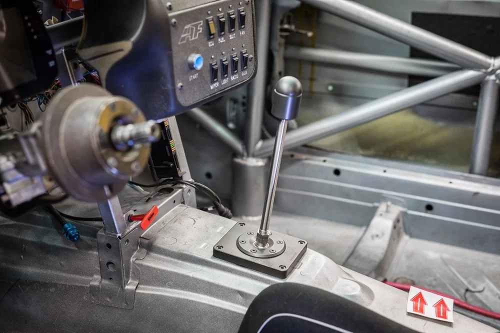 Stripped race car interior with shifter, switch panel and roll cage tubing fabricated in-house