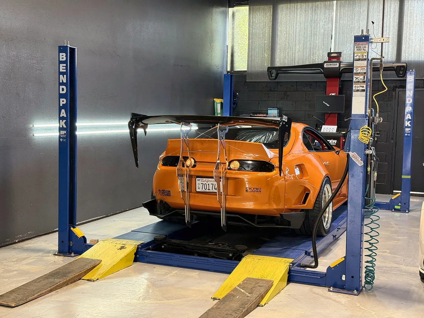 Orange Toyota Supra raised on a BendPak lift for service at Artec Automotive