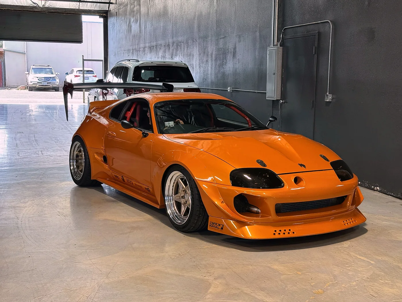 Orange Toyota Supra with widebody arches parked in the Artec Automotive workshop