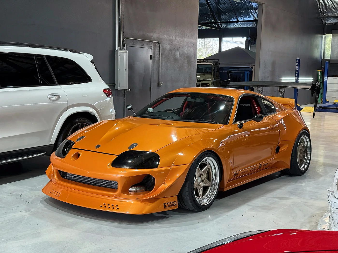 Front three-quarter view of an orange widebody Toyota Supra at Artec Automotive