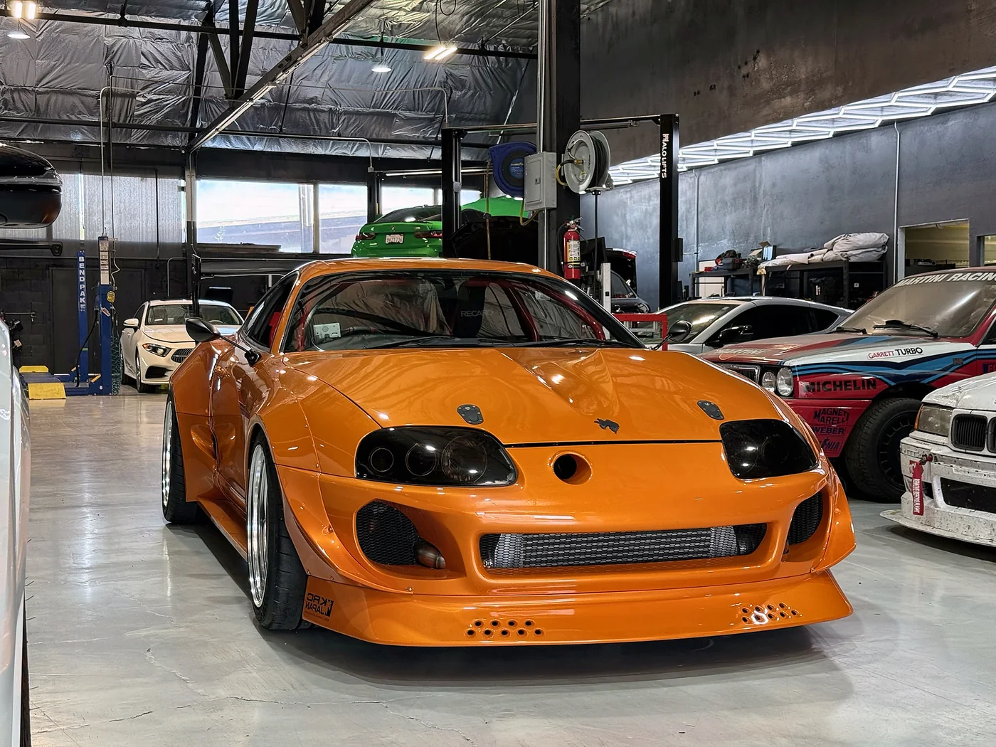Orange Toyota Supra with the front bumper removed during a build at Artec Automotive