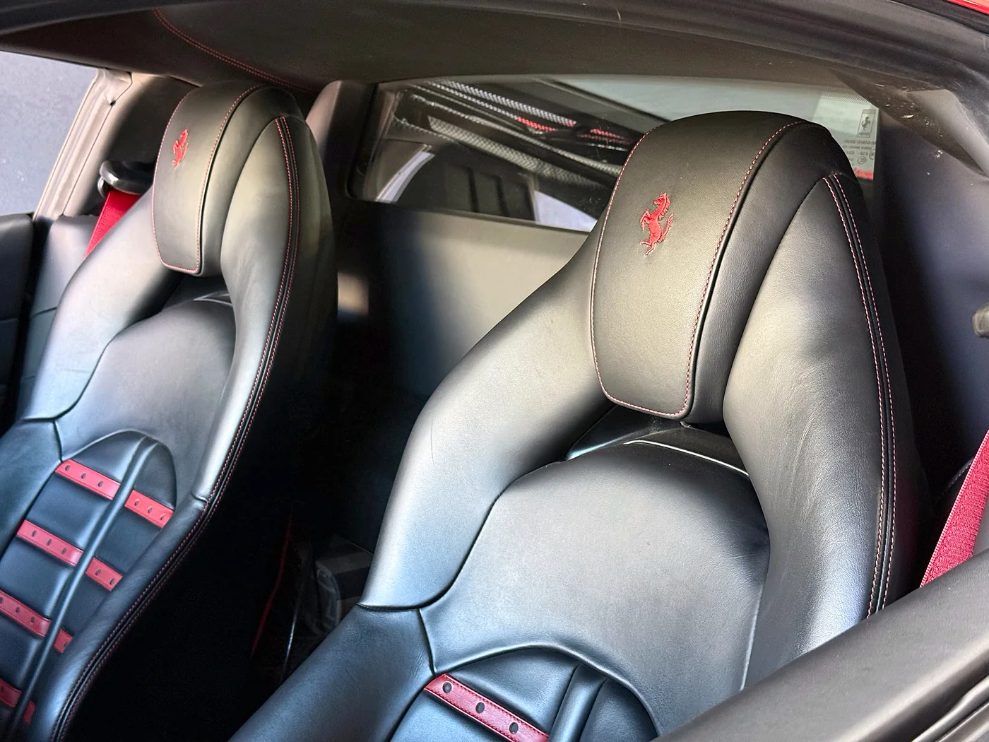 Black leather Ferrari seats with the prancing horse headrest emblem