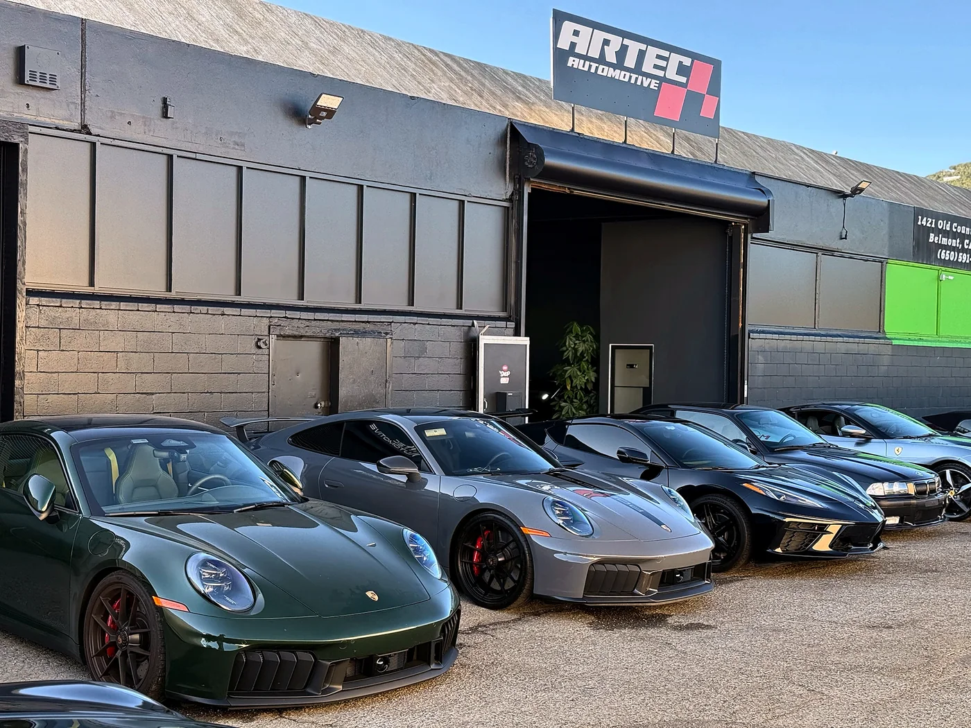 Porsche 911s and a Ferrari parked outside the Artec Automotive shop front