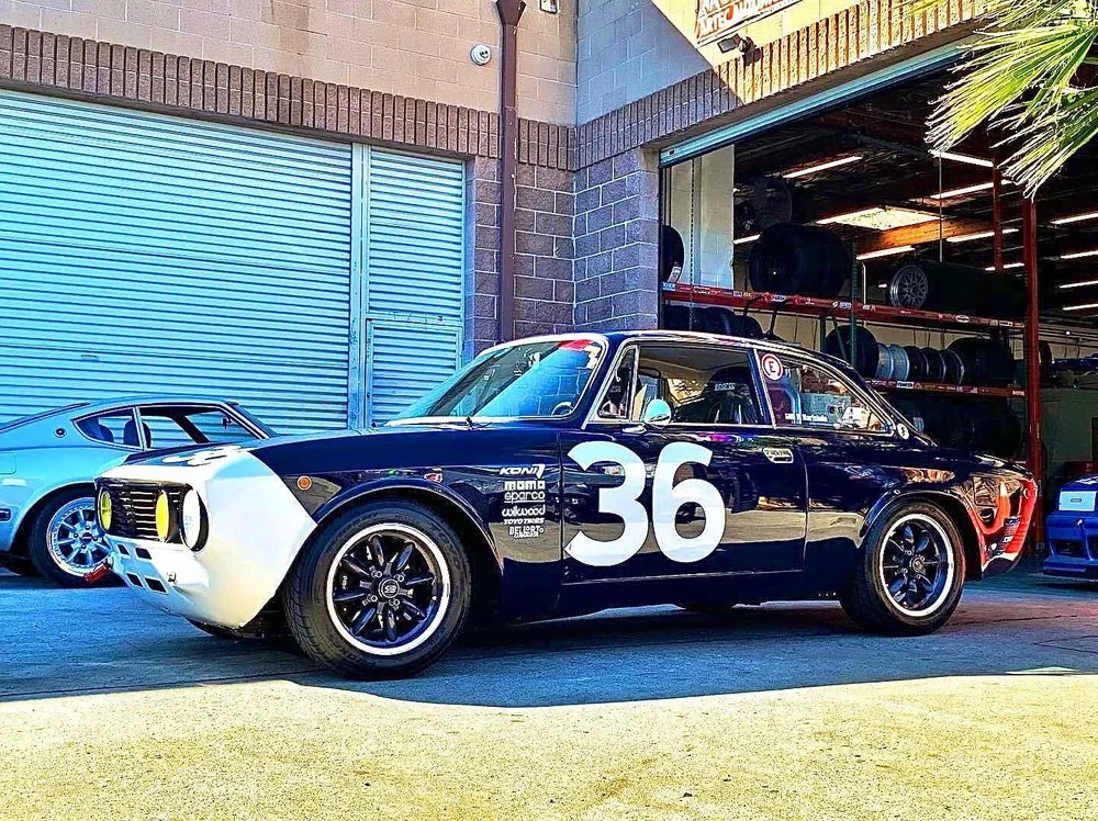 Blue and white BMW 2002 vintage race car number 36 outside the Artec Automotive shop