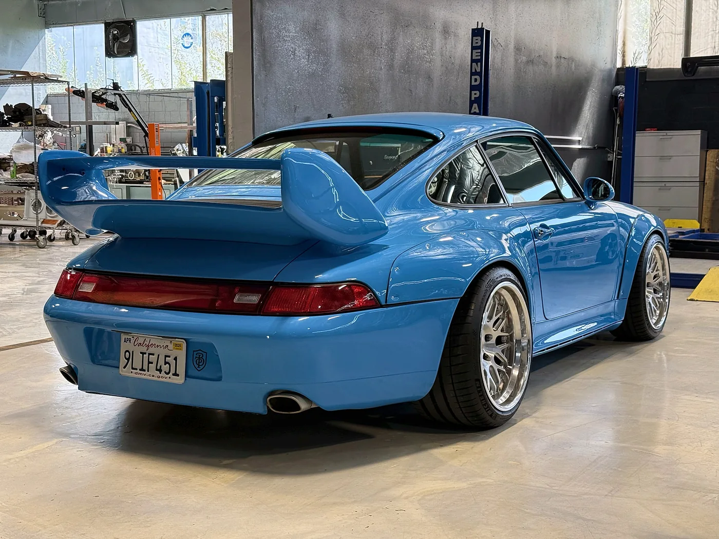 Riviera Blue Porsche 993 with a whale tail spoiler and gold wheels at Artec Automotive