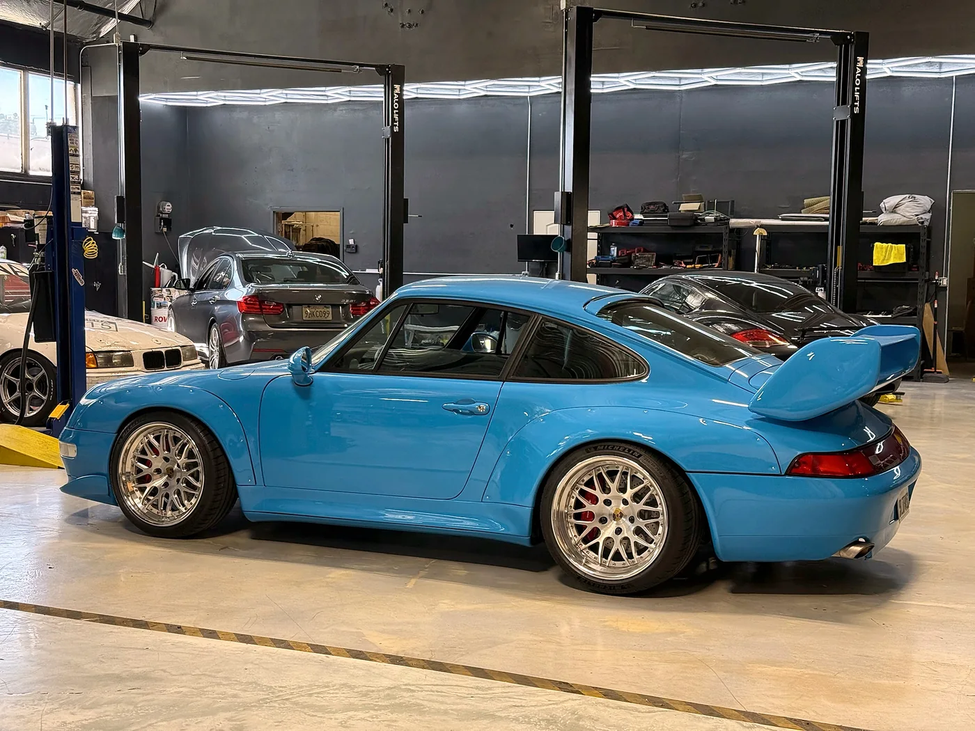 Rear three-quarter view of a Riviera Blue Porsche 993 RS in the workshop