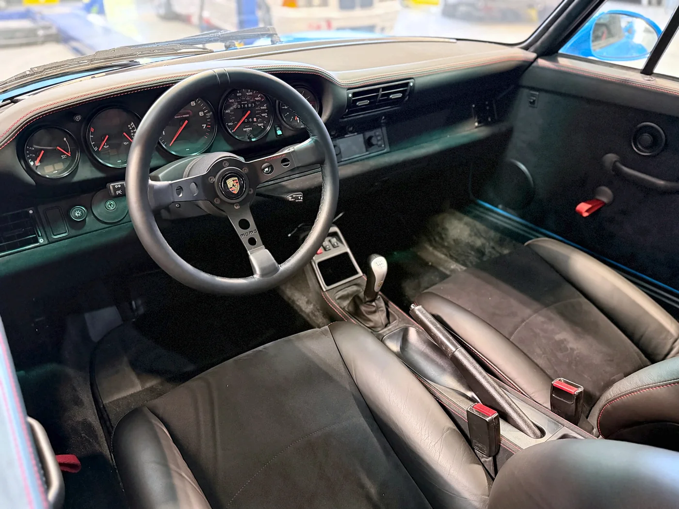 Classic Porsche 911 interior with a three-spoke steering wheel and manual shifter