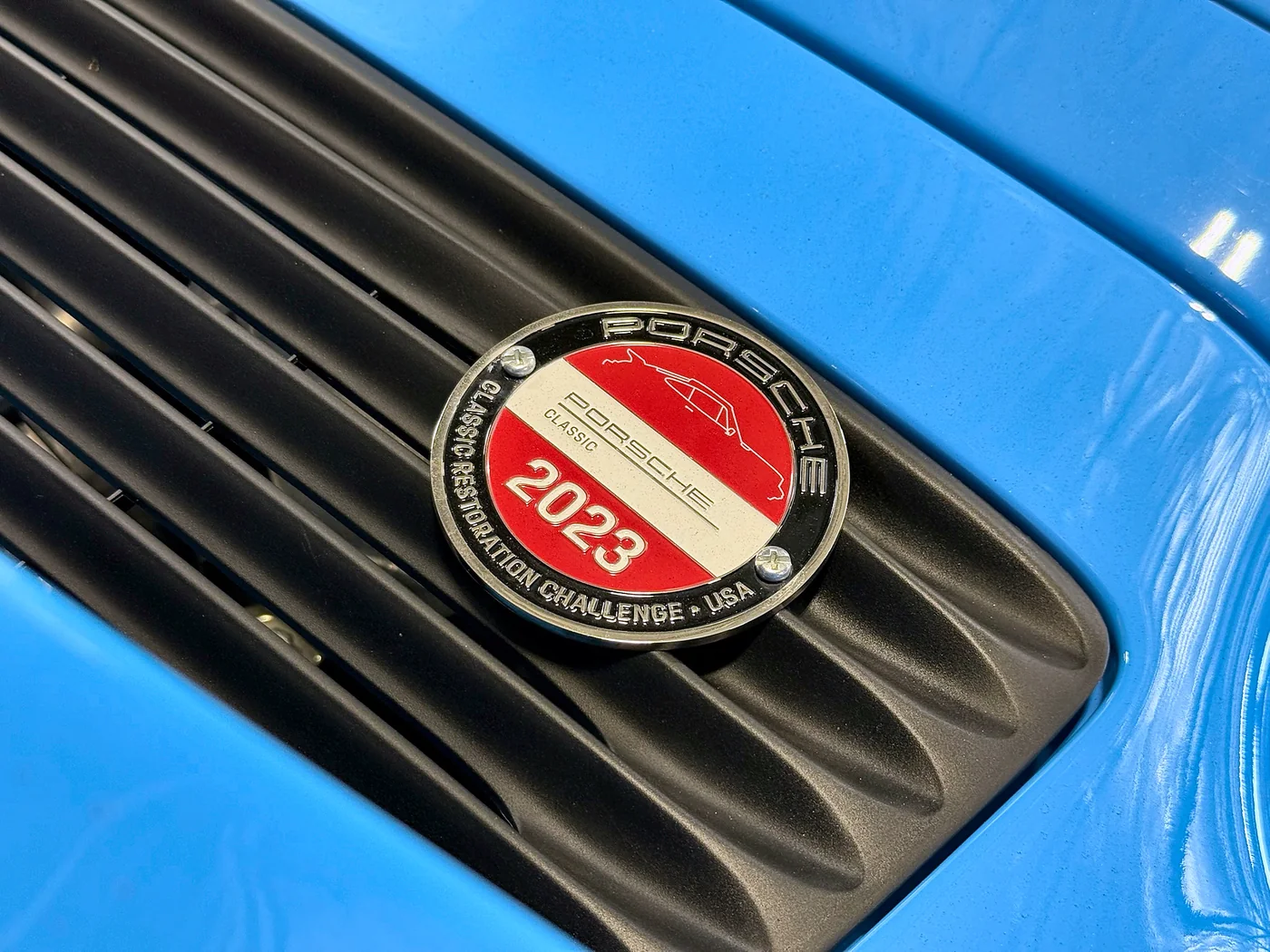 Porsche Parade 2023 Concours d’Elegance badge on a blue Porsche engine cover