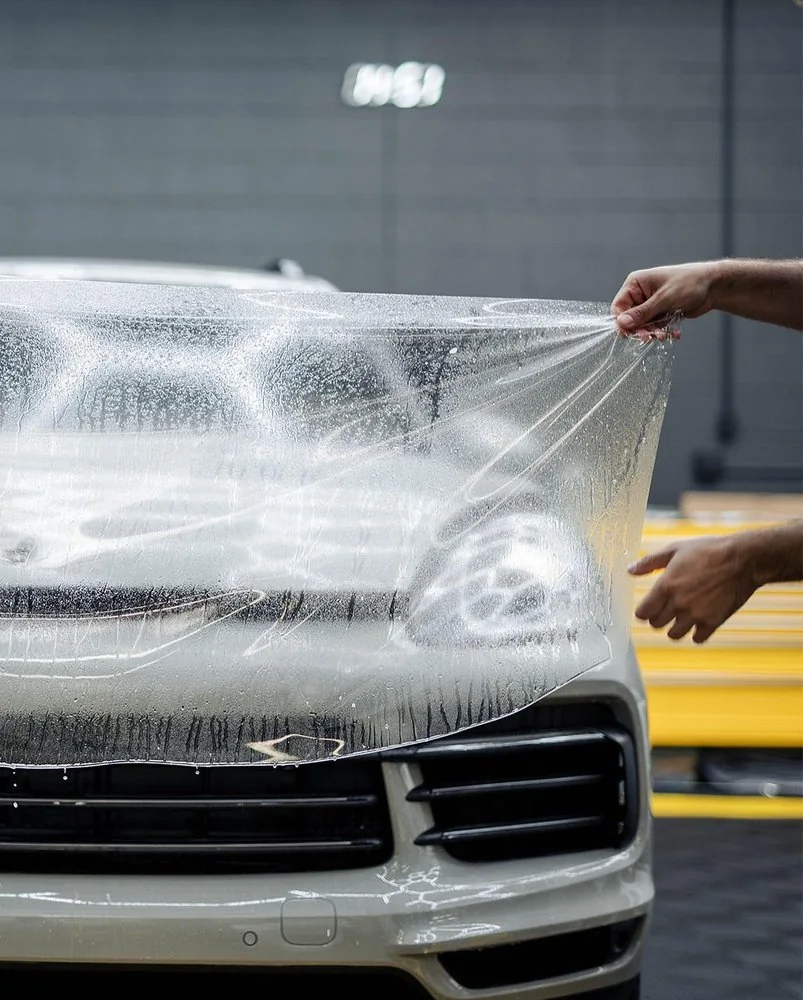 Installer applying paint protection film to the front bumper of a Porsche at Artec Automotive
