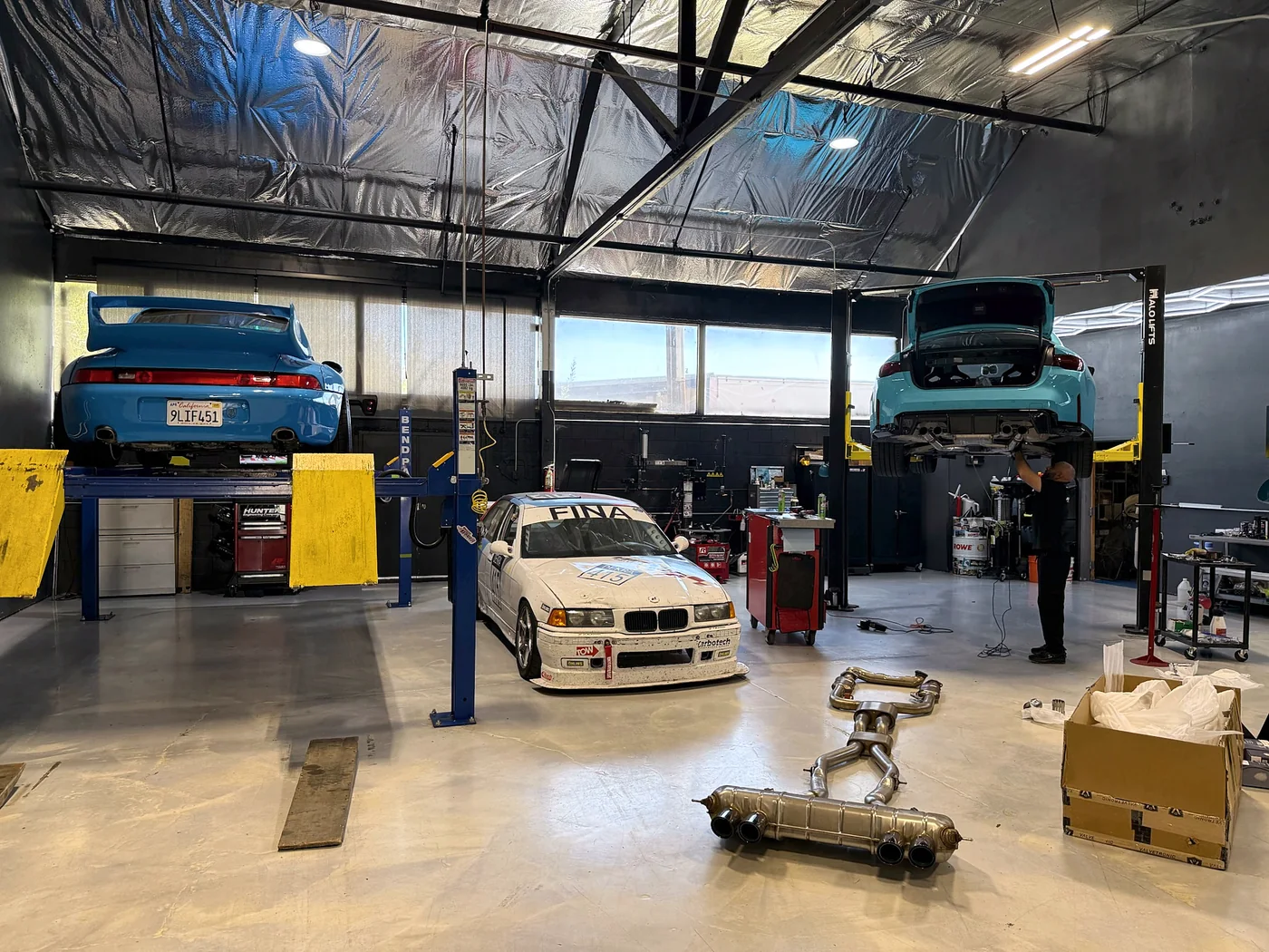 BMW raised on a two-post lift with an exhaust system on the floor beneath