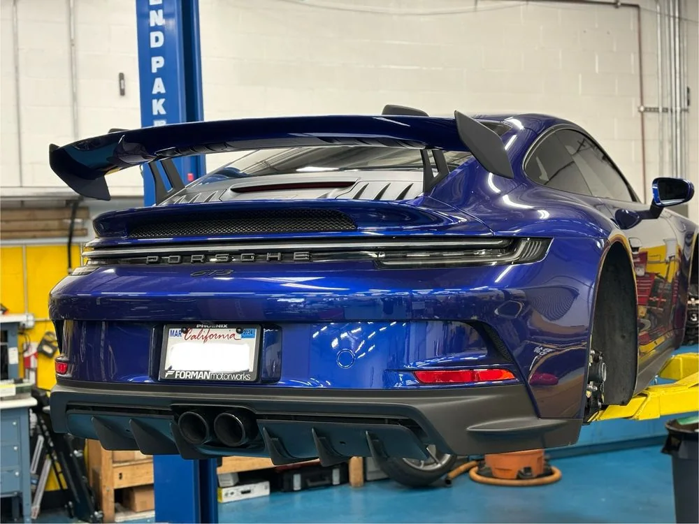 Rear of a blue Porsche 911 on the workshop floor after service