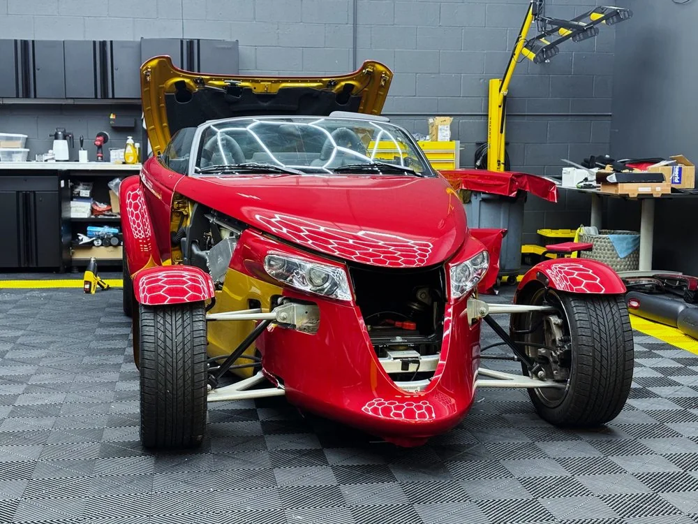 Red sports car with front bodywork removed during a full restoration at Artec Automotive