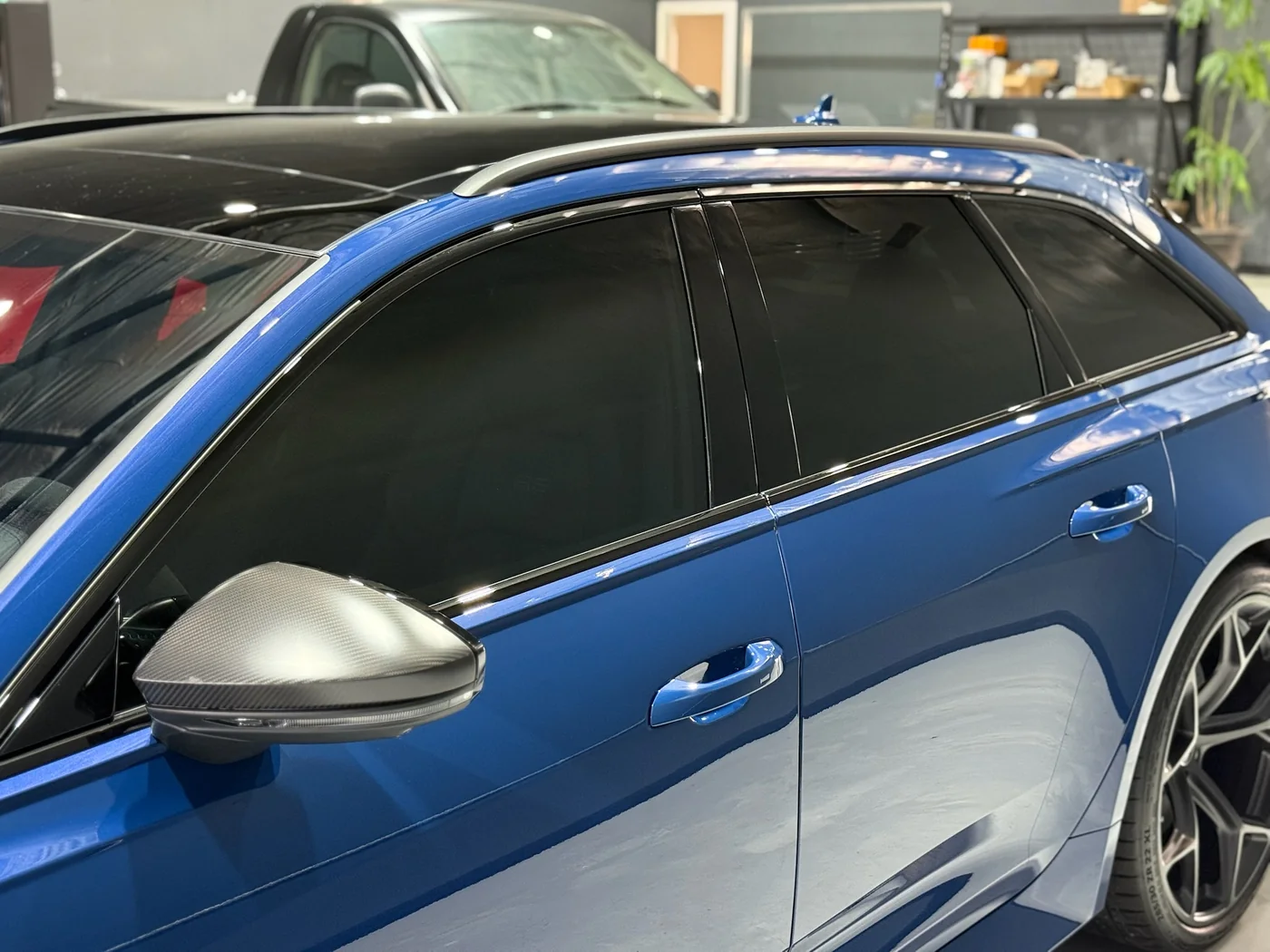 Side profile and mirror detail of a blue Audi RS6 after paint correction