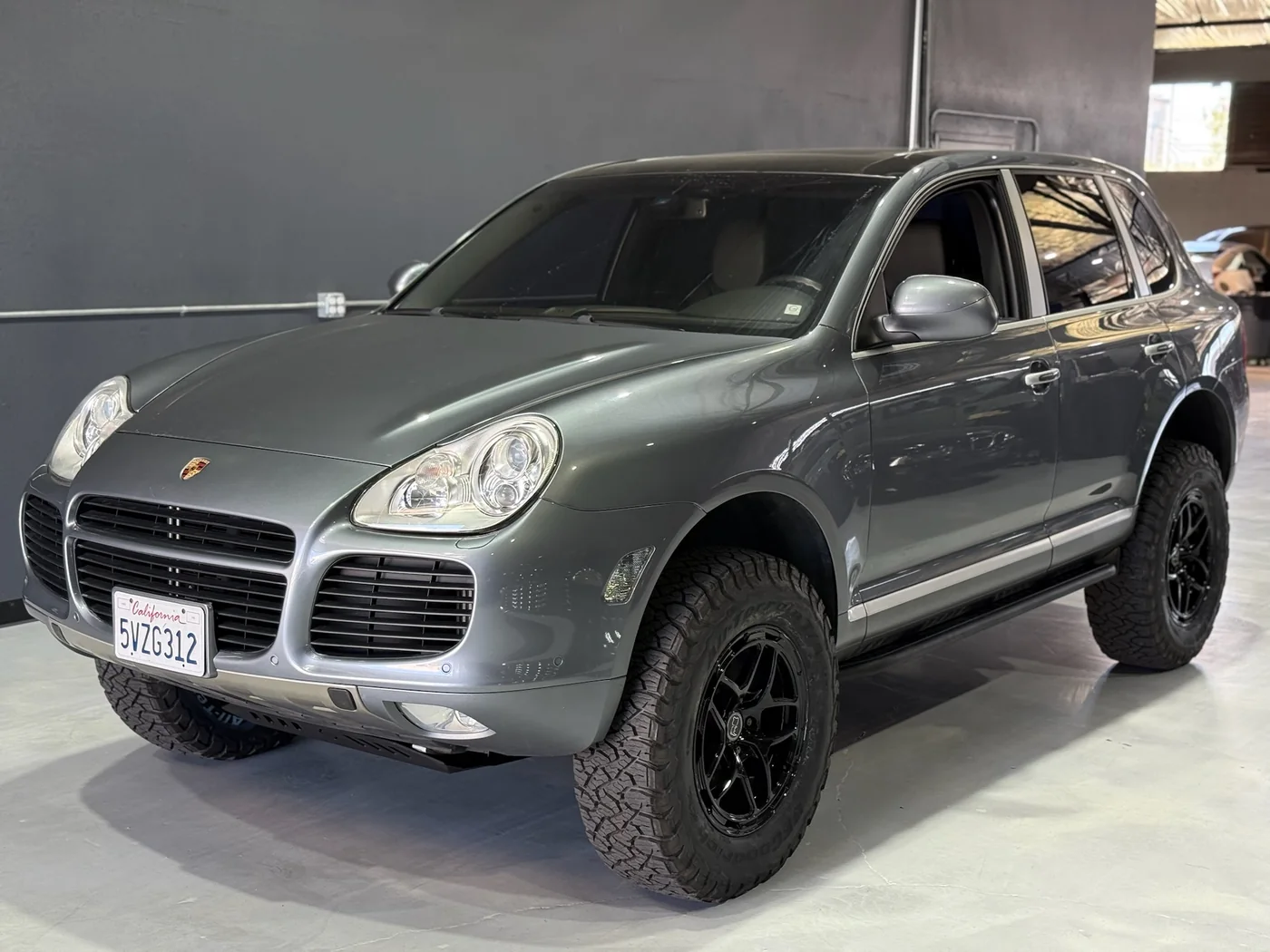 Silver Porsche Cayenne lifted on off-road tires and black wheels
