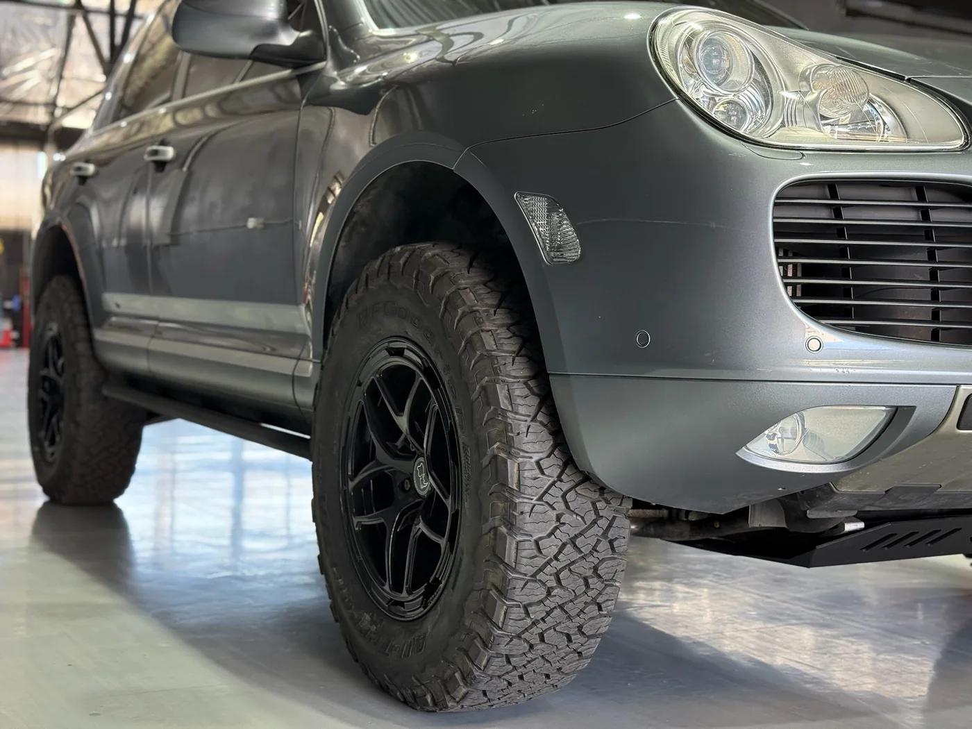 Front wheel and all-terrain tire detail on a lifted Porsche Cayenne