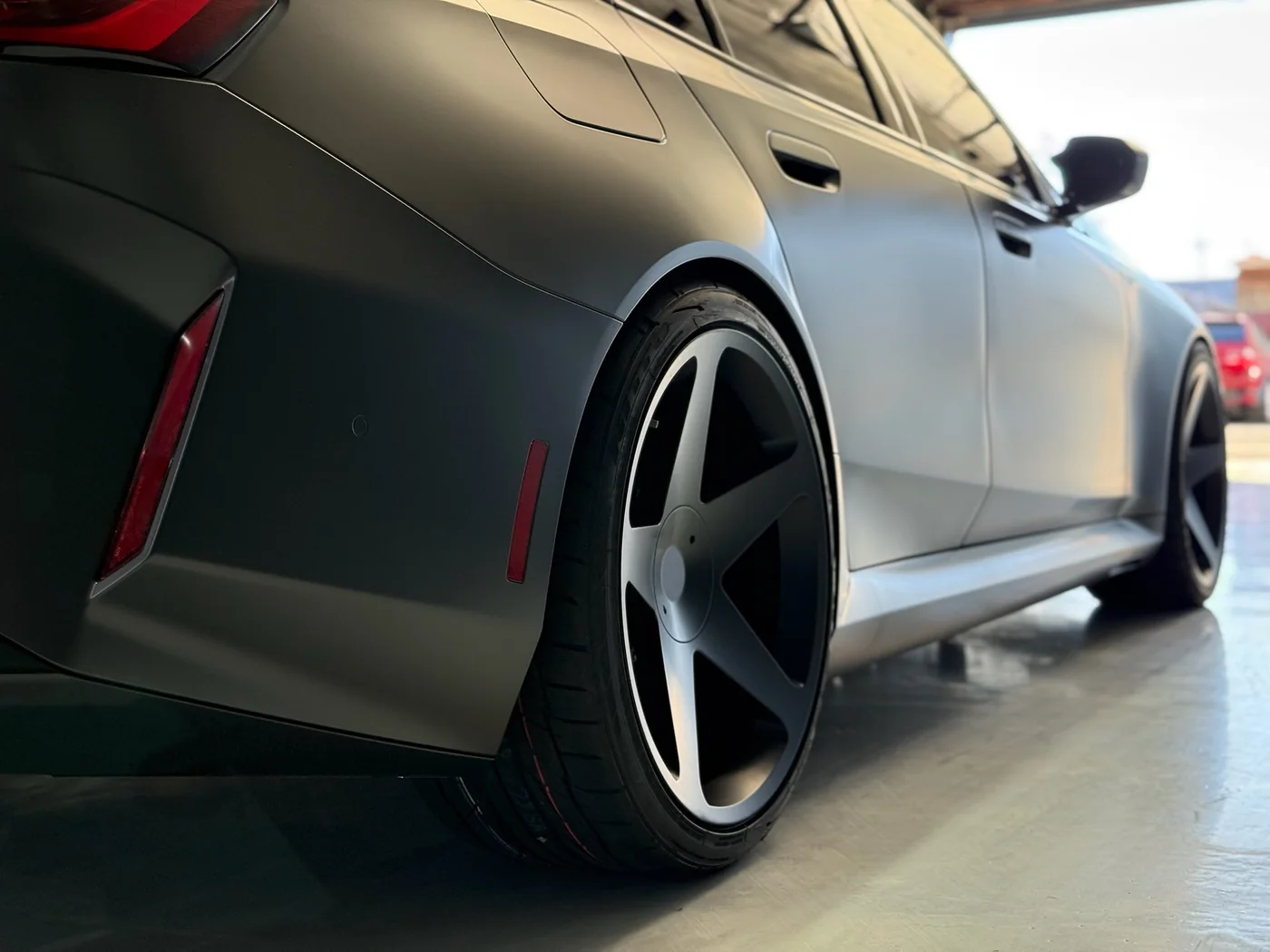 Wheel and lower body detail of a satin-wrapped Mercedes-AMG sedan