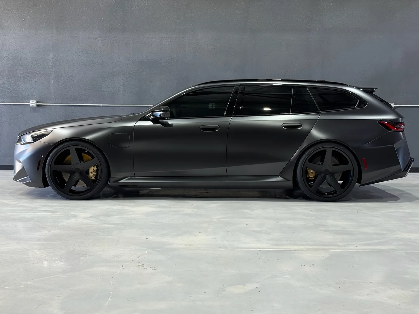 Matte black Audi RS6 Avant photographed side-on in the shop
