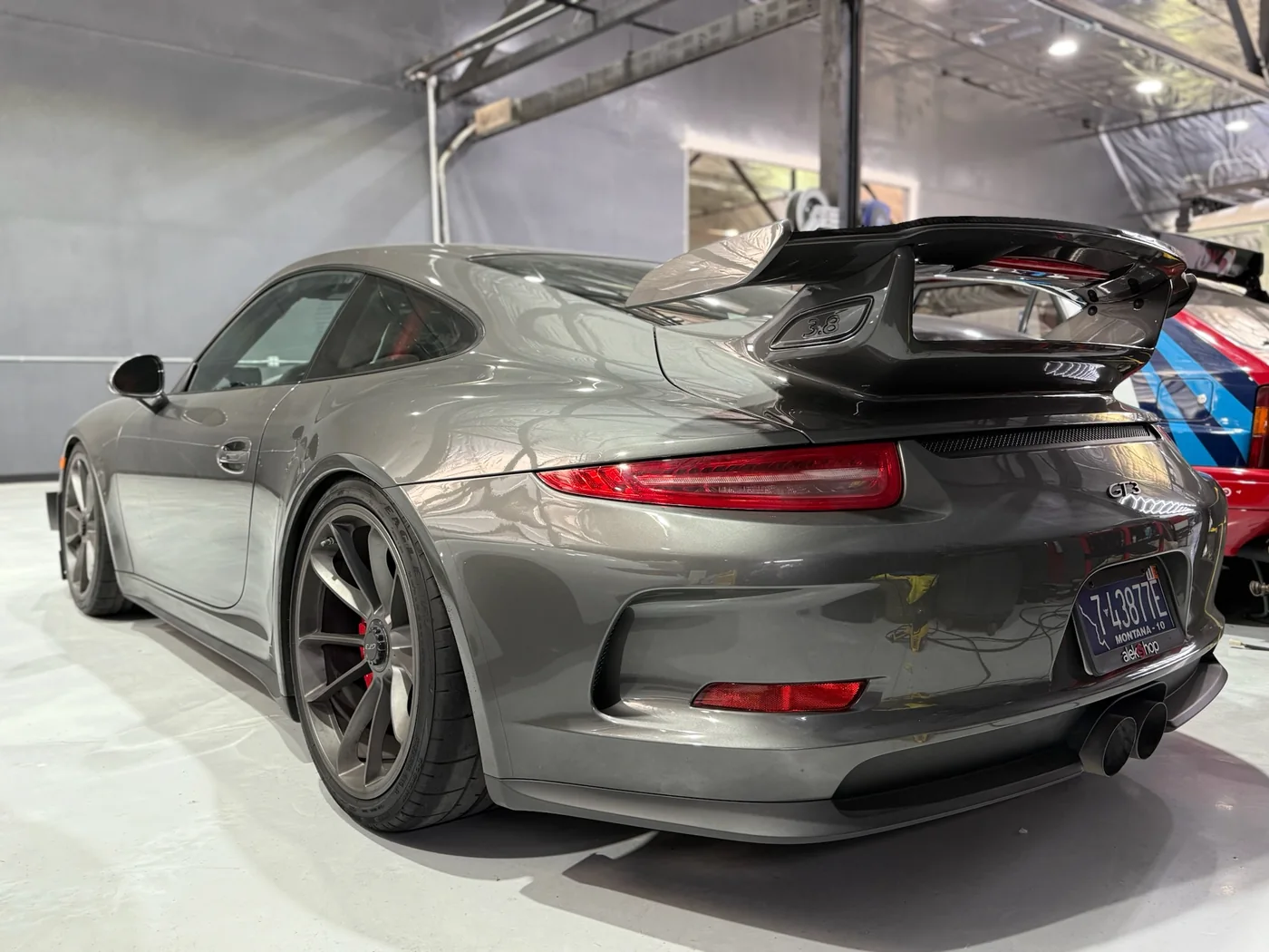 Grey Porsche 911 GT3 with rear wing inside the Belmont workshop