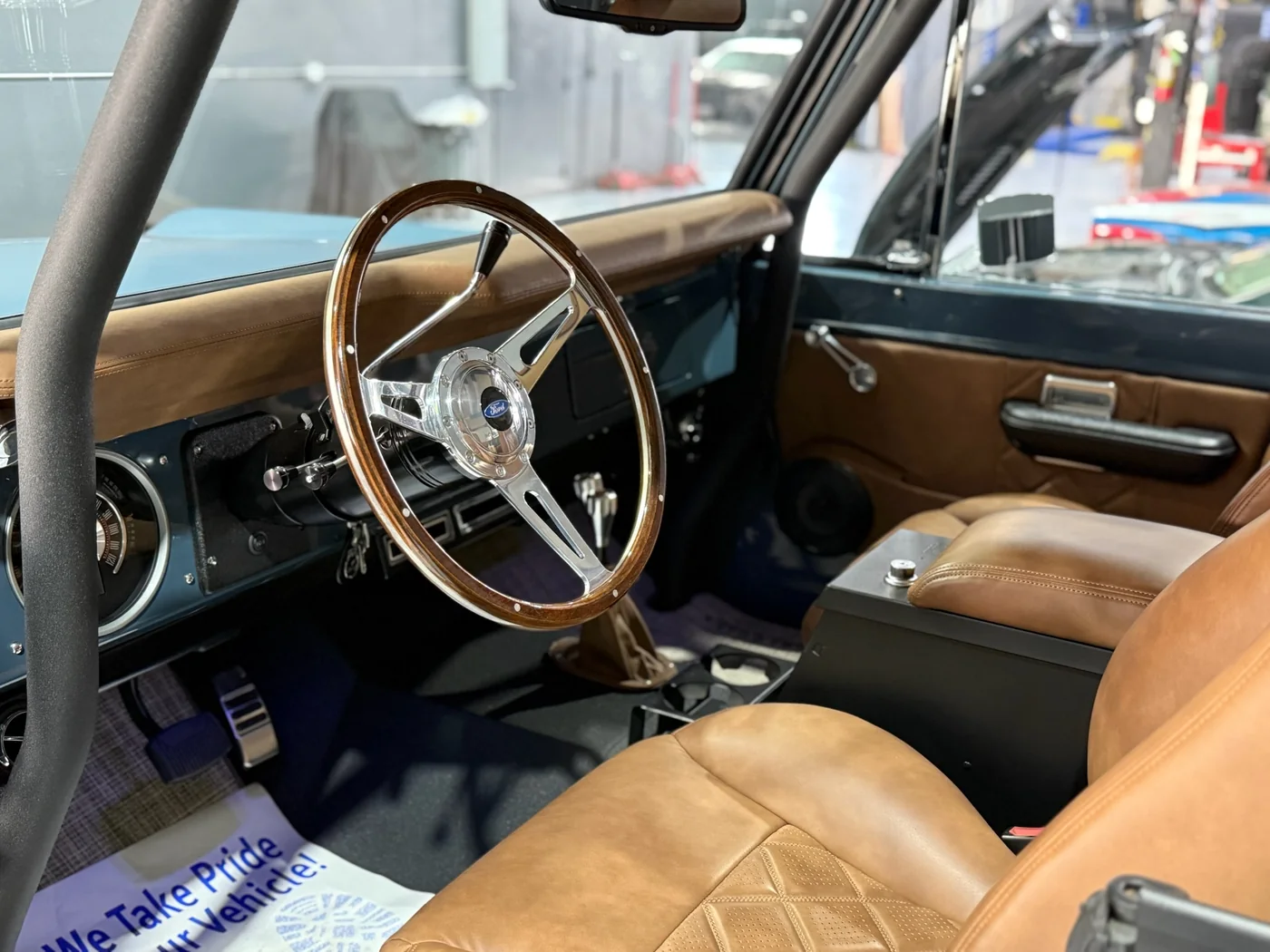 Wood-rimmed steering wheel and tan leather interior of a restored Ford Bronco