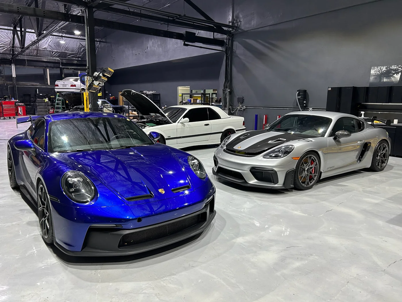 Blue Porsche 911 GT3 and a silver Mercedes-AMG GT parked in the service bay