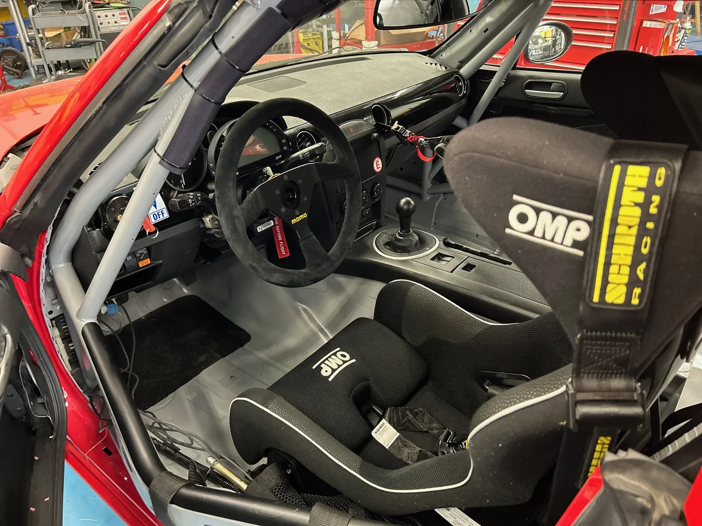 Stripped race car interior with OMP steering wheel, roll cage and racing seat
