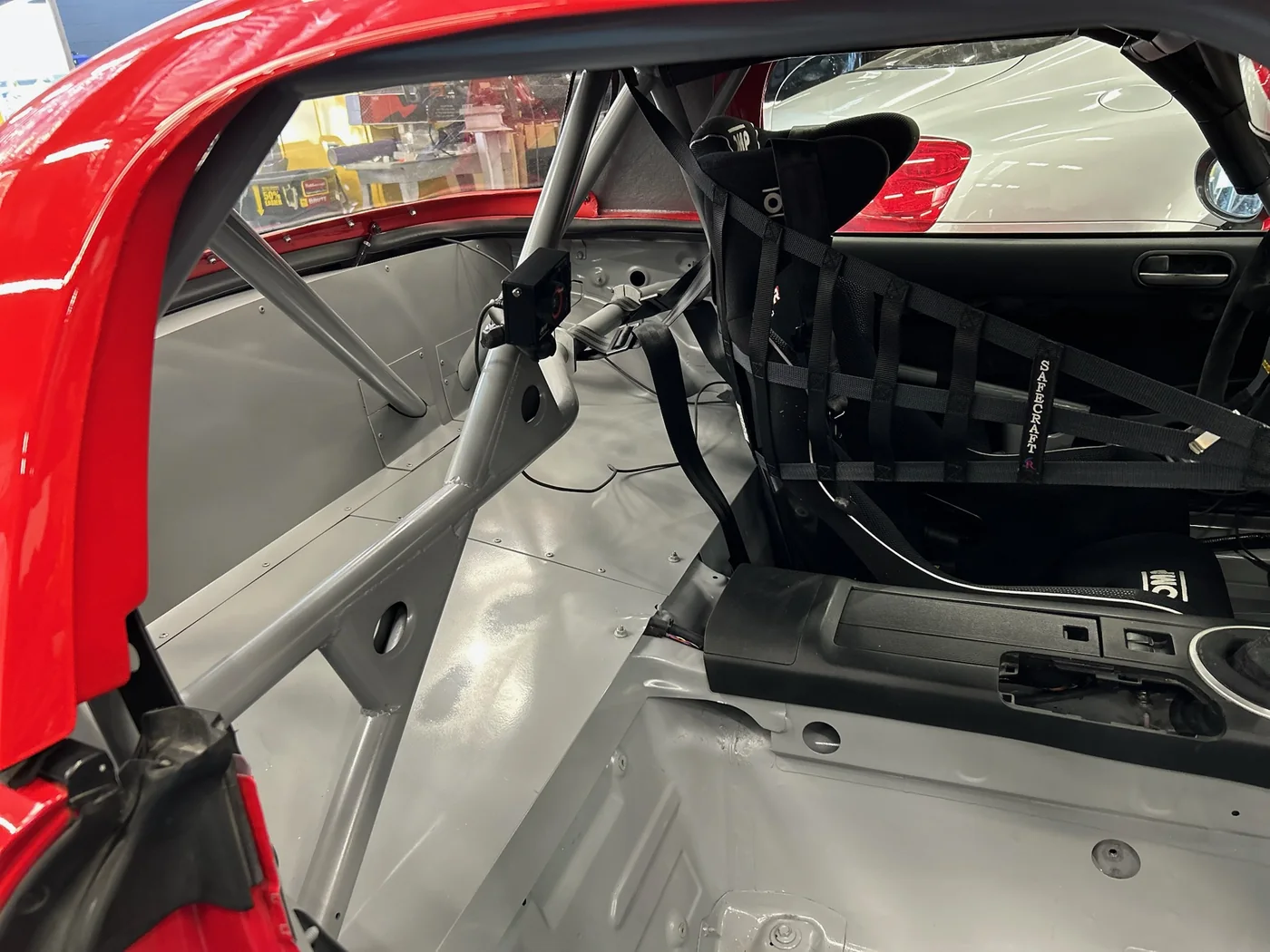 Roll cage and bare interior of a race car under construction at Artec Automotive