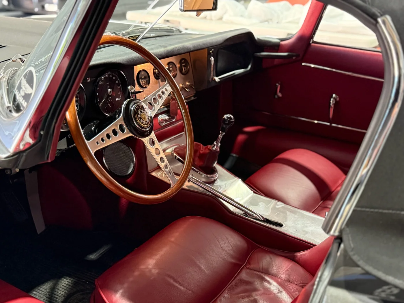 Wood-rimmed steering wheel and red leather interior of a restored classic car