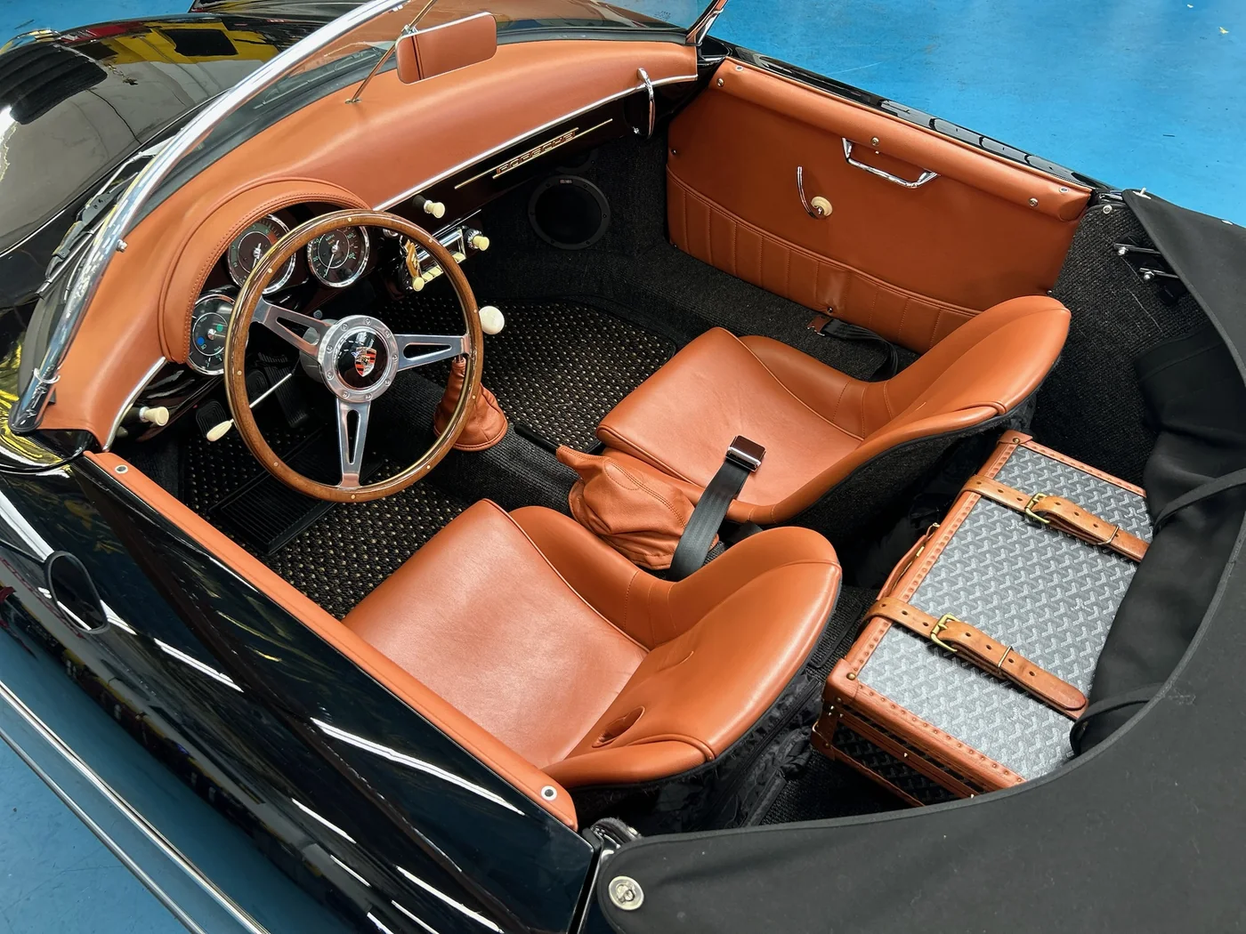 Tan leather interior and wood steering wheel of a classic Porsche 356