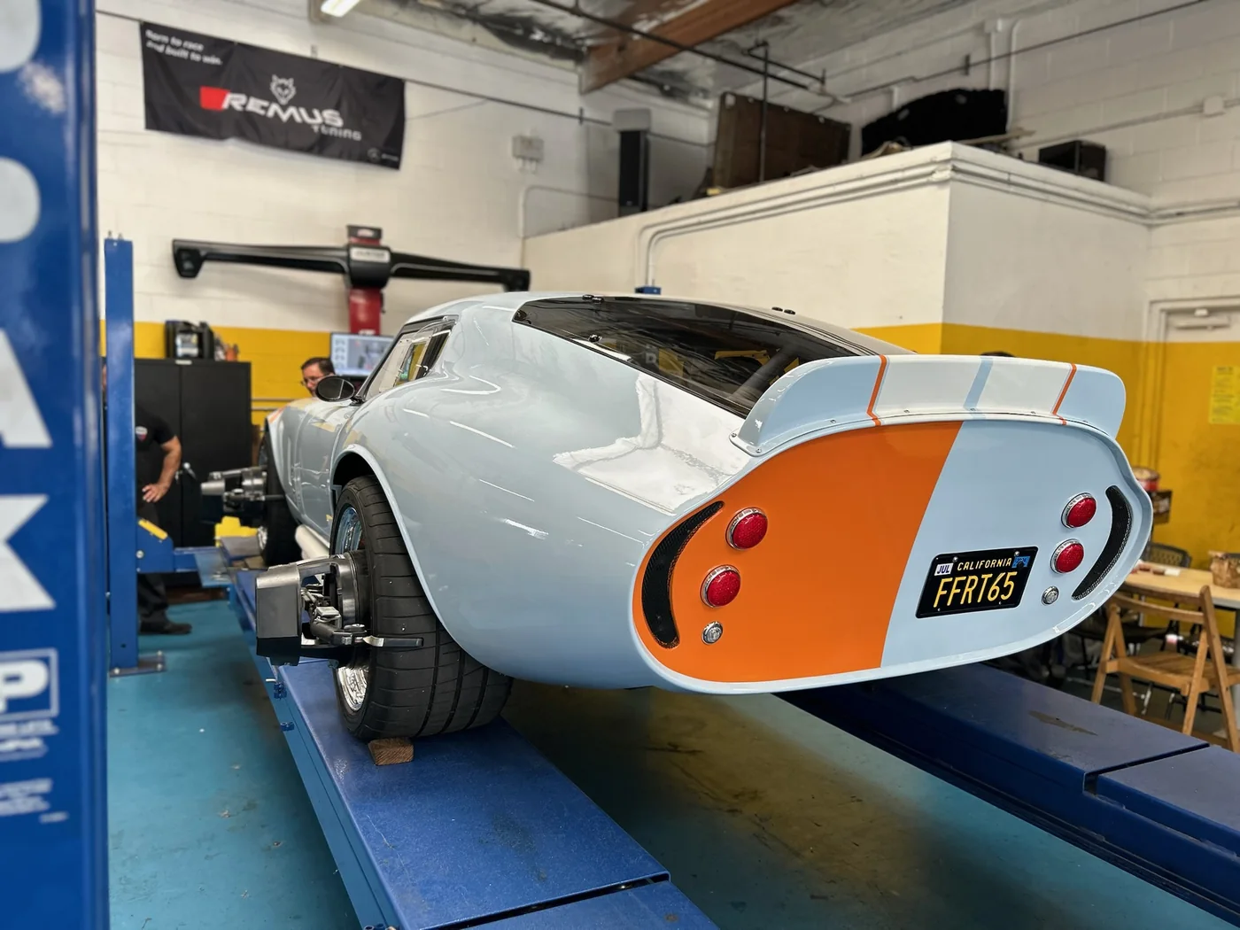 Silver Porsche 550 Spyder replica with racing roundels on the shop floor