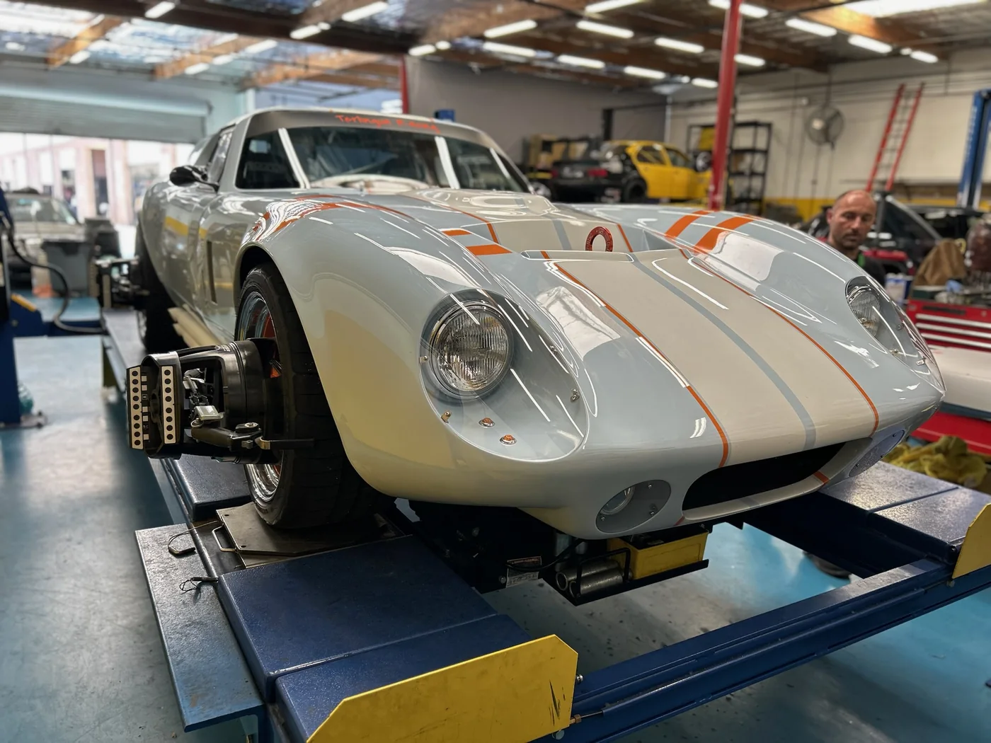 Vintage Porsche race car with number roundels being prepared in the workshop